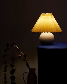 a yellow lamp sitting on top of a table next to a vase