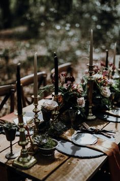 a wooden table topped with lots of candles and plates covered in flowers on top of it