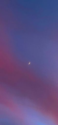 an airplane flying in the sky with a half moon above it and some clouds below