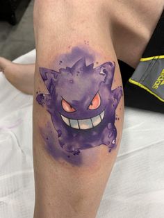 a person with a purple tattoo on their leg and the image of an angry cat