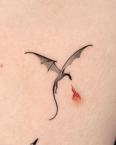 a small tattoo on the back of a woman's left shoulder with a bird flying over it