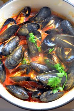 a pot filled with mussels and sauce on top of a stove