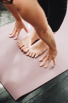 a person standing on top of a pink yoga mat