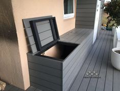 an empty box sitting on top of a wooden deck next to a potted plant