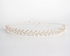 a gold headband with leaves on the side and pearls in the middle, sitting on a white surface