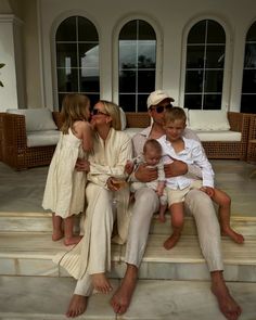 a family sitting on steps in front of a house with two children and one adult