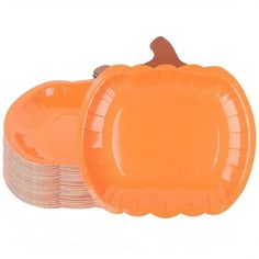 orange plates stacked on top of each other in front of a white background with an orange pumpkin