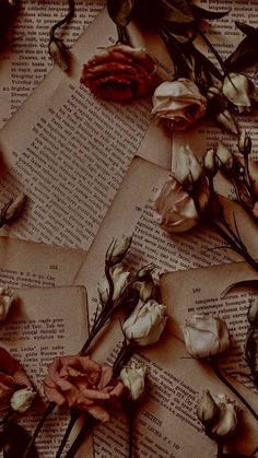 some flowers are laying on top of an old book with pages scattered around them and the paper is torn off