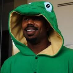 a man in a frog costume is smiling and looking at the camera while wearing a hoodie