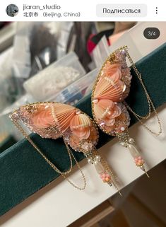 two butterfly shaped brooches sitting on top of a green table next to a mirror