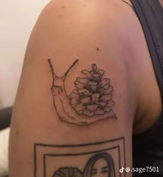 a woman's arm with a tattoo on it that has a picture of a snail and flowers