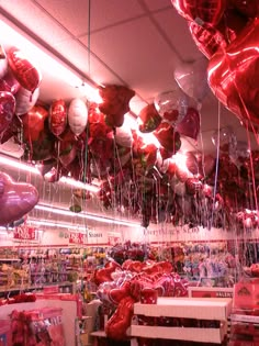 red and white balloons are hanging from the ceiling in a store with other items on display