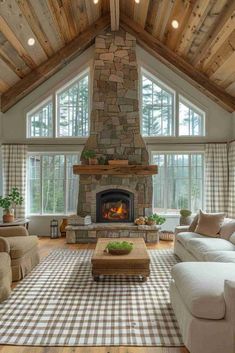 a living room with a large stone fireplace in the center and lots of windows on both sides