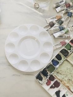 some paint and watercolors are on a table next to an empty tray with paints