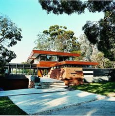 a modern house in the middle of a lush green park with stairs leading up to it