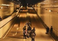 several people are standing on the side of a road at night with their backs turned to the camera