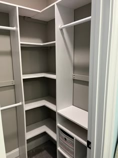 an empty walk - in closet with white shelves and gray carpeted flooring is shown