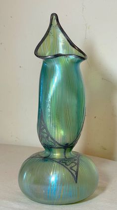 a green glass vase sitting on top of a table