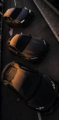 two black sports cars parked next to each other on the side of a road at night