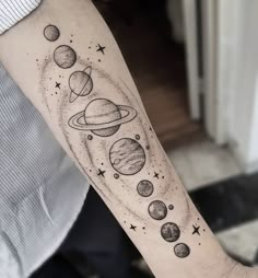 a person with a tattoo on their arm that has planets and stars around it,