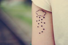 a woman's arm with a cloud and hearts tattoo on it