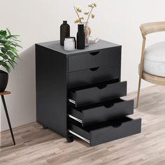 three drawers are stacked on top of each other in front of a chair and potted plant