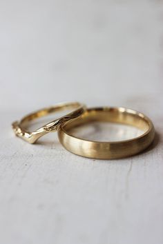 two gold wedding rings sitting on top of each other