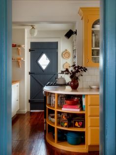 an open door leading into a kitchen with yellow cabinets and wood flooring on the side