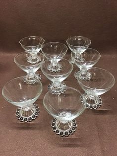 six clear glass bowls with beaded rims on each one side and an ornate design in the middle