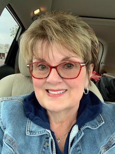 a woman wearing glasses sitting in the back seat of a car