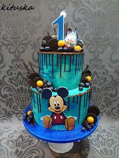 a mickey mouse birthday cake with blue icing and fondant decorations on the top