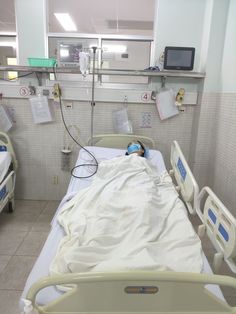 an empty hospital bed with medical equipment in the background