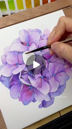 someone is painting a flower with watercolors