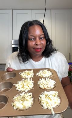 a woman holding a tray with cupcakes in it