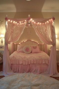 a bed with pink sheets and lights on the headboard is shown in this bedroom