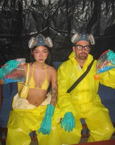 a man and woman in yellow costumes sitting on a blue couch with plastic bags over their heads