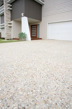 an empty driveway with a house in the background and grass on the ground next to it