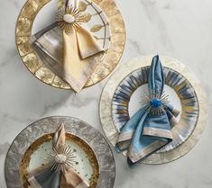 three plates with napkins on them sitting on a marble counter top next to each other