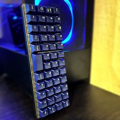 a blue computer keyboard sitting on top of a wooden table next to a mouse pad