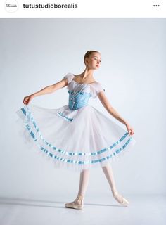 a young ballerina in a white and blue dress