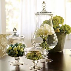 three glass vases filled with flowers on top of a wooden table