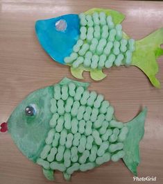 two fish made out of gummy balls on top of a wooden table next to each other