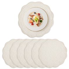 a white plate topped with fruit on top of a pile of placemats next to each other