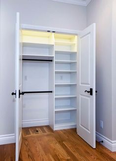 an empty white closet with open doors and shelves on either side of the door is a wooden floor