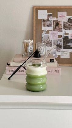 a stack of books sitting on top of a white table next to a glass vase