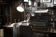 an old fashioned typewriter sitting on top of a wooden table in a room filled with books