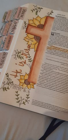 an open bible with flowers and the letter f on it, next to some scissors