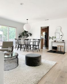 a living room filled with furniture next to a dining room table and chairs on top of a white rug