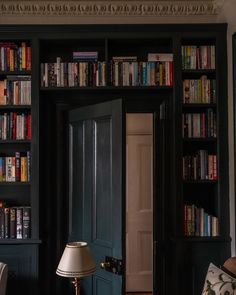 a living room with bookshelves full of books and a lamp in the corner