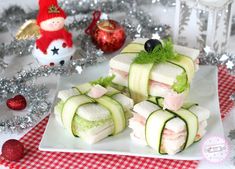 cucumber sandwiches are arranged on a white plate with christmas decorations in the background